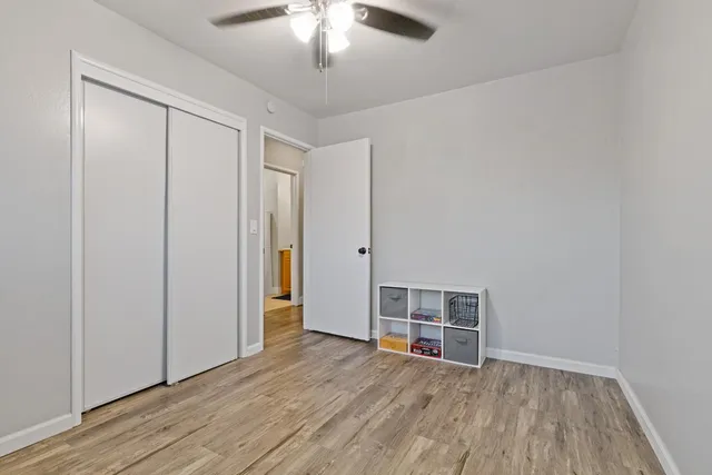 an empty room with wooden floor closet and windows