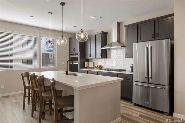 a kitchen with stainless steel appliances a refrigerator a stove a sink and chairs