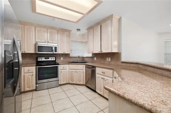 a kitchen with granite countertop a stove sink and refrigerator