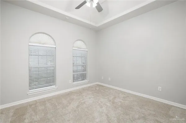 an empty room with windows and ceiling fan