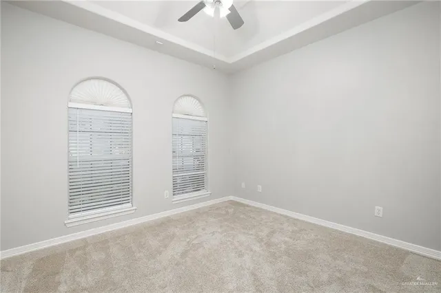 an empty room with windows and ceiling fan