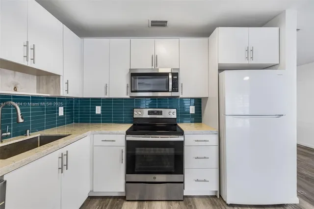 a kitchen with white cabinets and stainless steel appliances