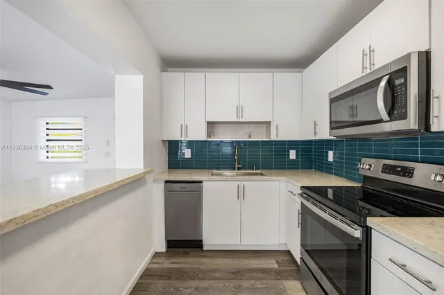 a kitchen with stainless steel appliances white cabinets and a stove top oven