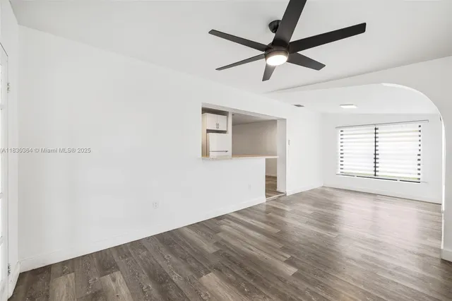 an empty room with wooden floor ceiling fan and windows