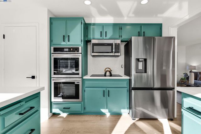 a kitchen with stainless steel appliances granite countertop a sink a stove and a refrigerator