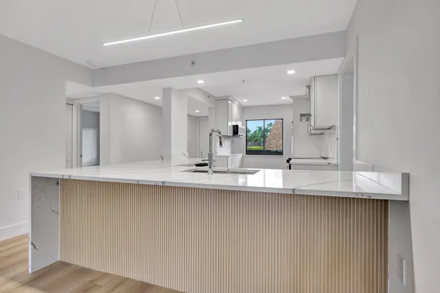 a large white kitchen with a sink and a large mirror of wooden cabinet