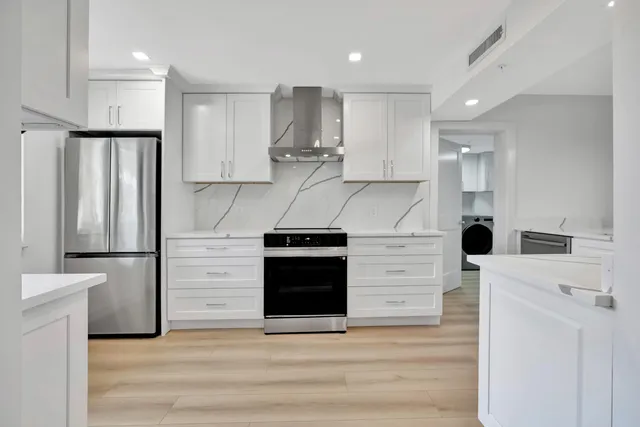 a kitchen with stainless steel appliances kitchen island a refrigerator sink and cabinets