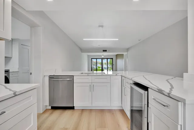 a kitchen with a sink cabinets stainless steel appliances and wooden floor