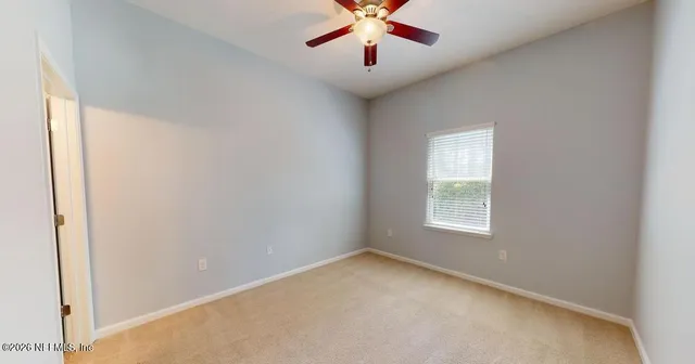an empty room with windows and fan