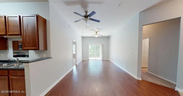 a view of a hallway with wooden floor and a bathroom