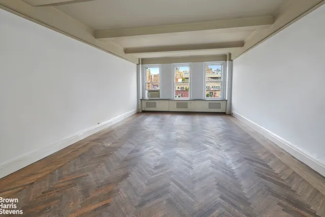 a view of a big room with windows and chandelier fan