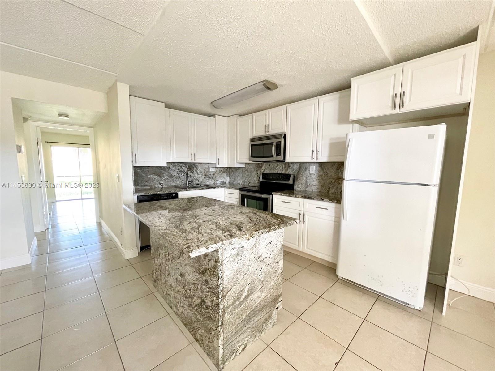 105 Meadows Circle, Unit 105 Boynton Beach, FL 33436 - Photo 2 of 18 a kitchen with stainless steel appliances granite countertop a refrigerator a stove a sink a microwave and cabinets