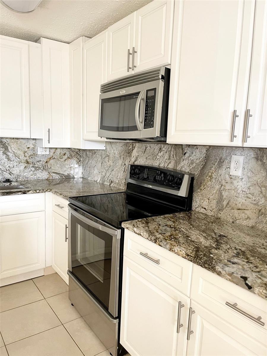 105 Meadows Circle, Unit 105 Boynton Beach, FL 33436 - Photo 3 of 18 a kitchen with granite countertop white cabinets and stainless steel appliances