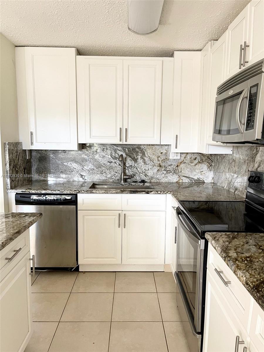 105 Meadows Circle, Unit 105 Boynton Beach, FL 33436 - Photo 4 of 18 a kitchen with granite countertop a sink a stove and cabinets