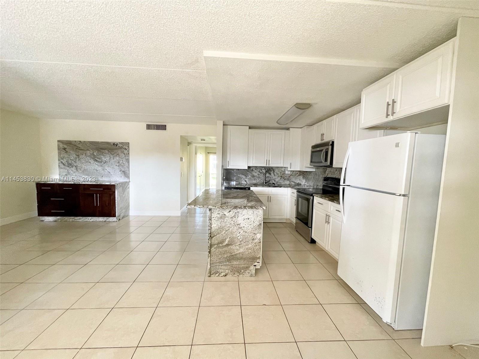 105 Meadows Circle, Unit 105 Boynton Beach, FL 33436 - Photo 7 of 18 a kitchen with granite countertop a refrigerator and a stove top oven