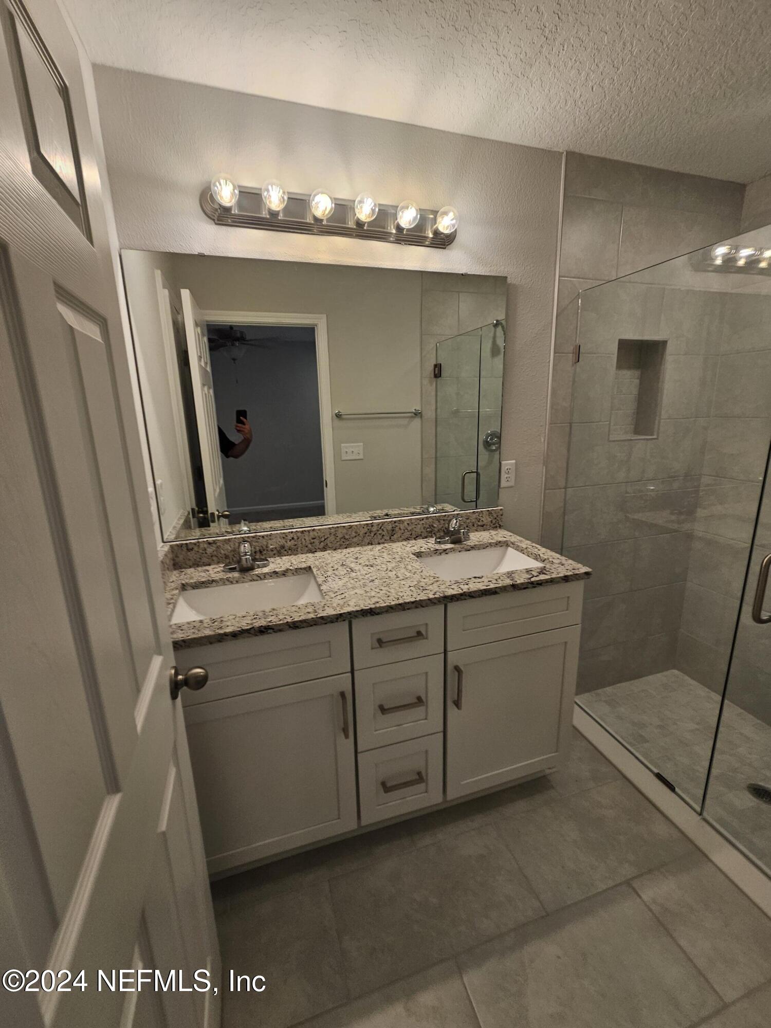7607 Del Road Jacksonville, FL 32244 - Photo 11 of 15 a bathroom with a granite countertop sink a mirror and a shower