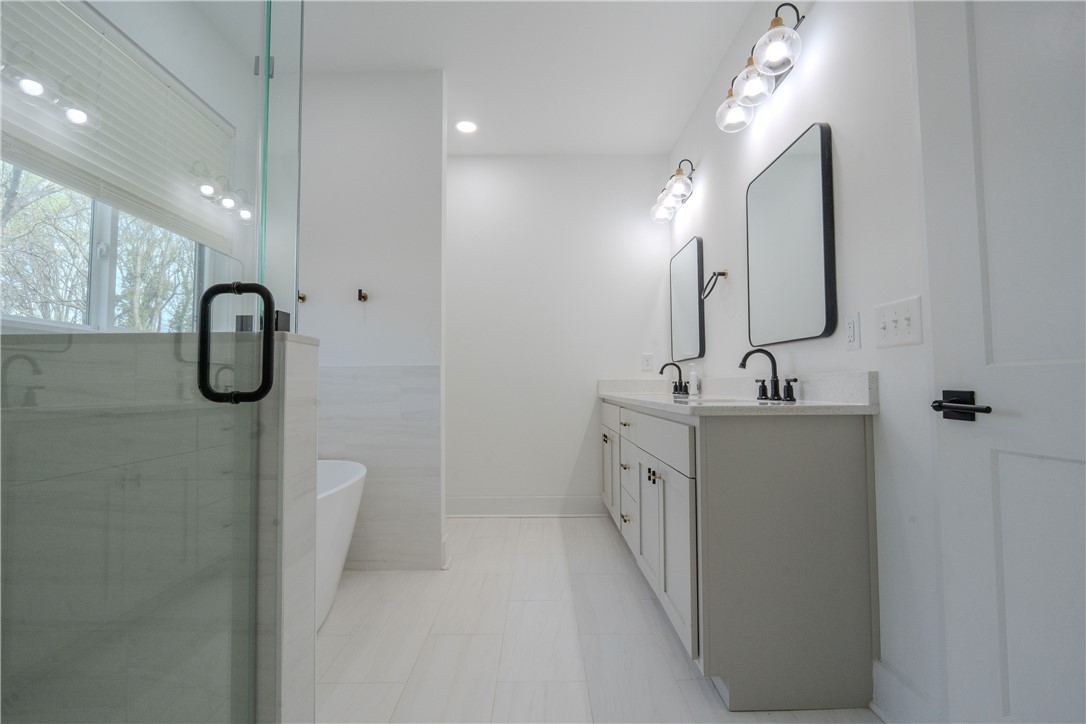 203 Mr Jim's Lane Clinton, SC 29325 - Photo 12 of 28 This bright bathroom features a spacious shower, a soaking tub, and a vanity with dual sinks.