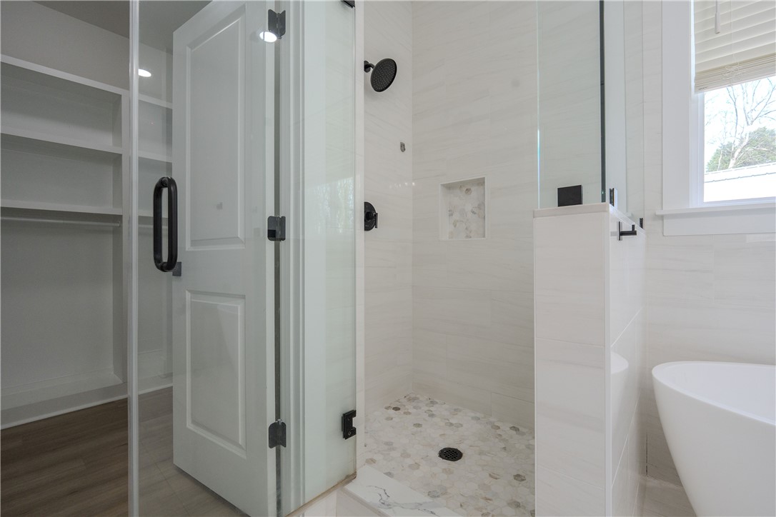 203 Mr Jim's Lane Clinton, SC 29325 - Photo 13 of 28 This modern bathroom features a spacious shower and a freestanding tub, offering a serene retreat.