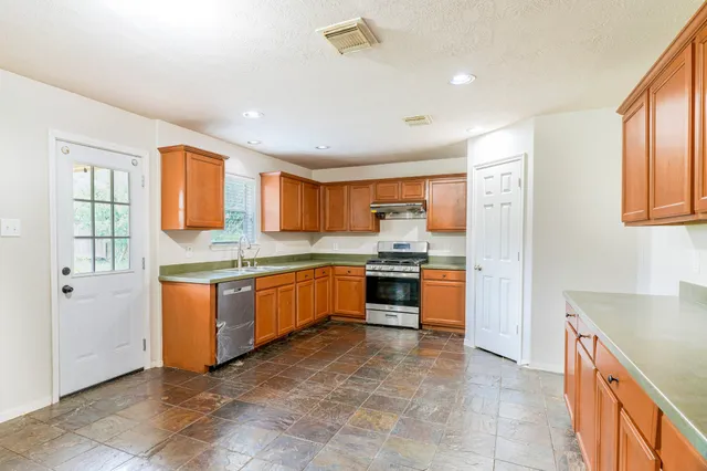 a kitchen with granite countertop a sink cabinets and stainless steel appliances