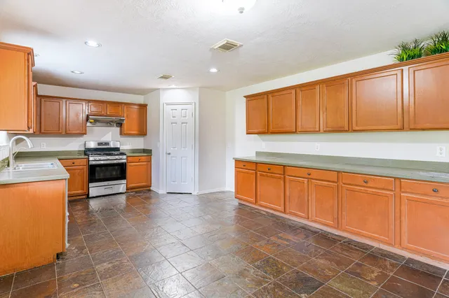 a kitchen with stainless steel appliances granite countertop a stove a sink and a refrigerator