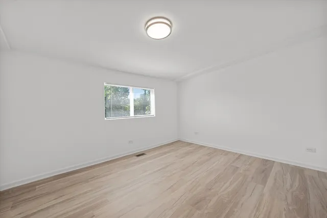 an empty room with a fan & a window