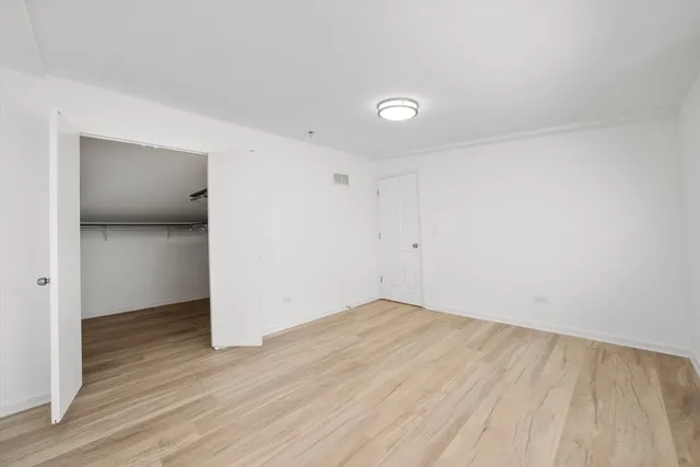 a view of an empty room with wooden floor and closet