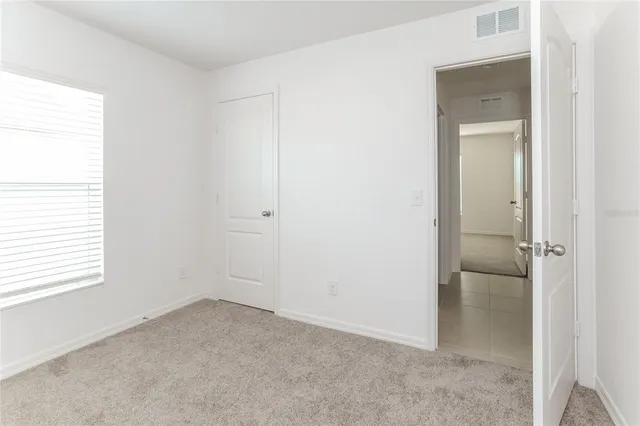 a view of an empty room with closet and a window