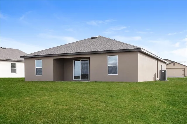 a front view of house with yard and trees in the background