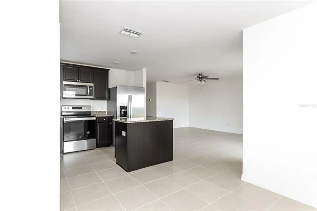 a kitchen with granite countertop a refrigerator and cabinets