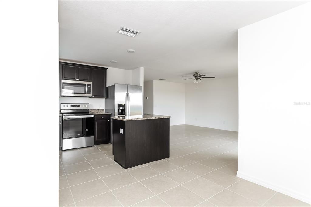 1724 Canaan Loop Dundee, FL 33838 - Photo 5 of 16 a kitchen with granite countertop a refrigerator and cabinets