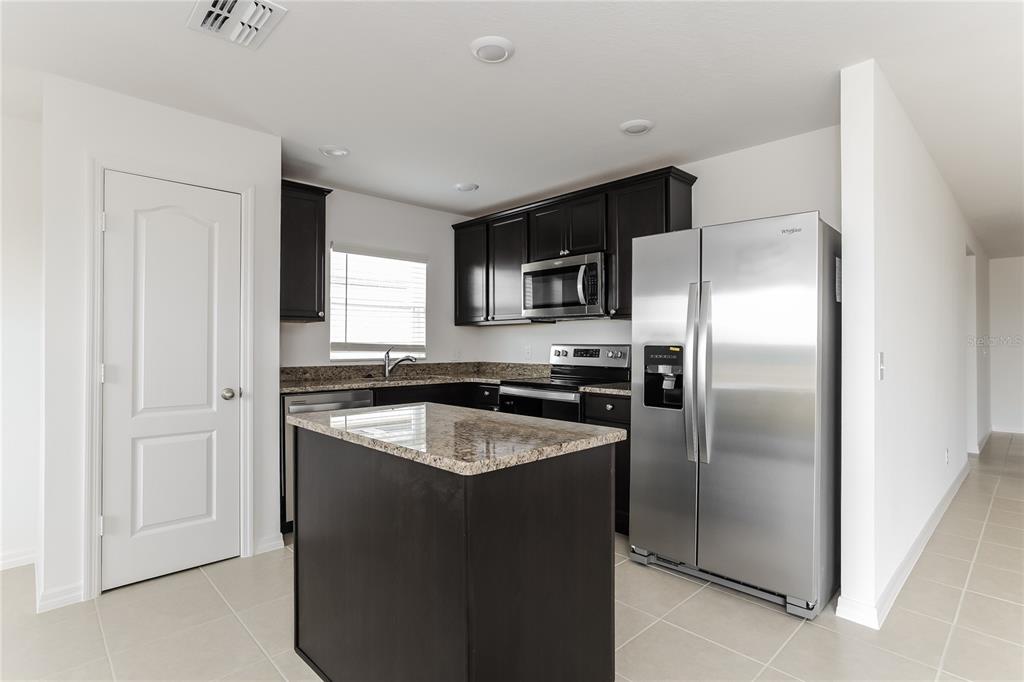 1724 Canaan Loop Dundee, FL 33838 - Photo 6 of 16 a kitchen with a refrigerator a microwave a sink and cabinets