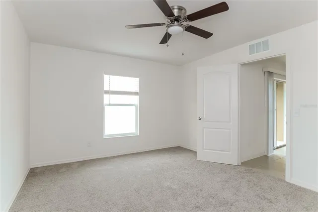 an empty room with a window and a fan