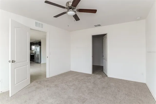 an empty room with closet and a ceiling fan