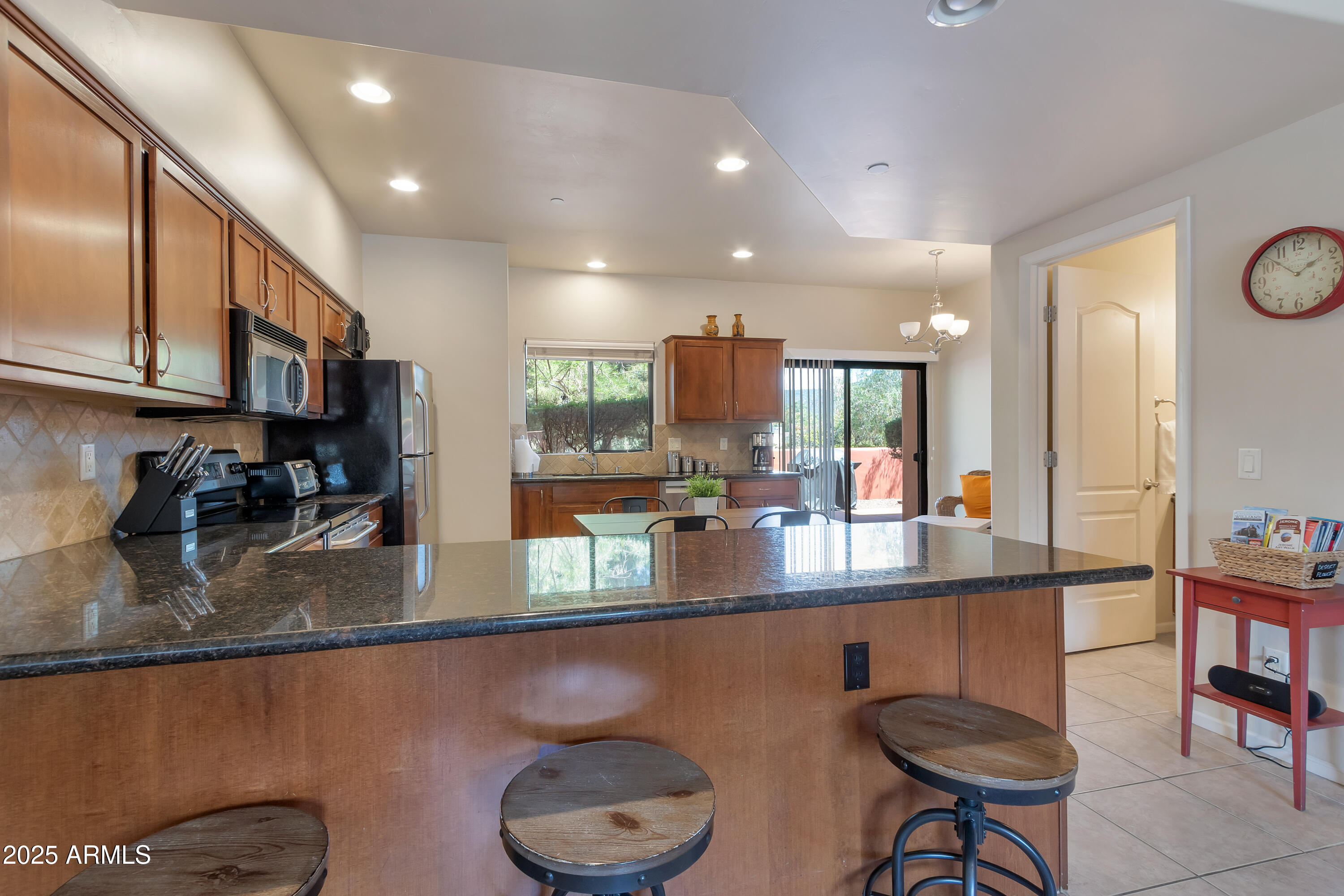 45 Canyon Diablo Road, Unit 5 Sedona, AZ 86351 - Photo 9 of 25 a kitchen with stainless steel appliances granite countertop a sink a stove a dining table and chairs with wooden floor