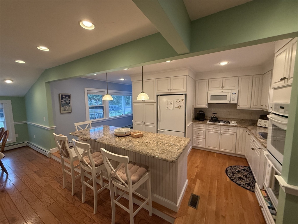40 Studley Road, Unit 1 Barnstable, MA 02601 - Photo 5 of 24 a kitchen with stainless steel appliances granite countertop a stove a sink a refrigerator white cabinets with wooden floor and chairs