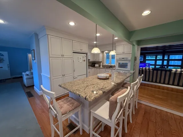 a kitchen with stainless steel appliances granite countertop a table chairs sink and cabinets