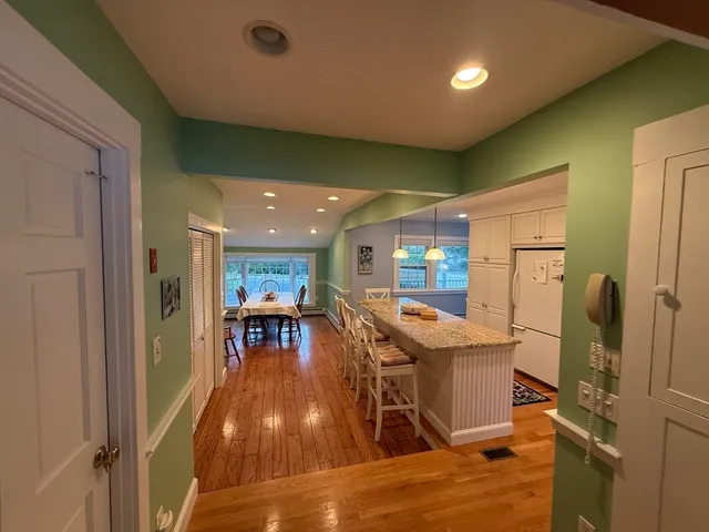 a kitchen with stainless steel appliances granite countertop furniture wooden floor and a view of living room