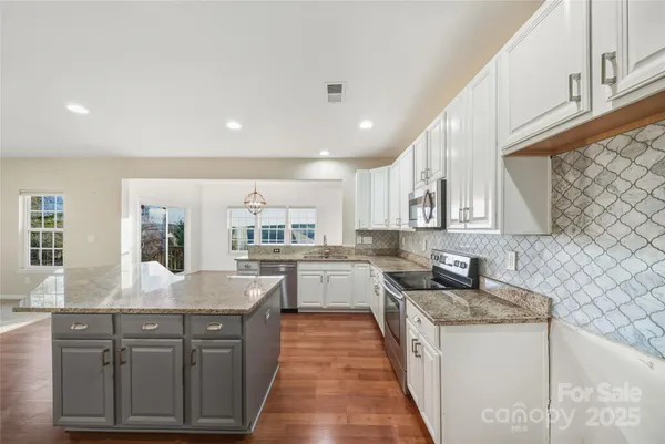 a large kitchen with stainless steel appliances granite countertop a sink counter space cabinets and a large window