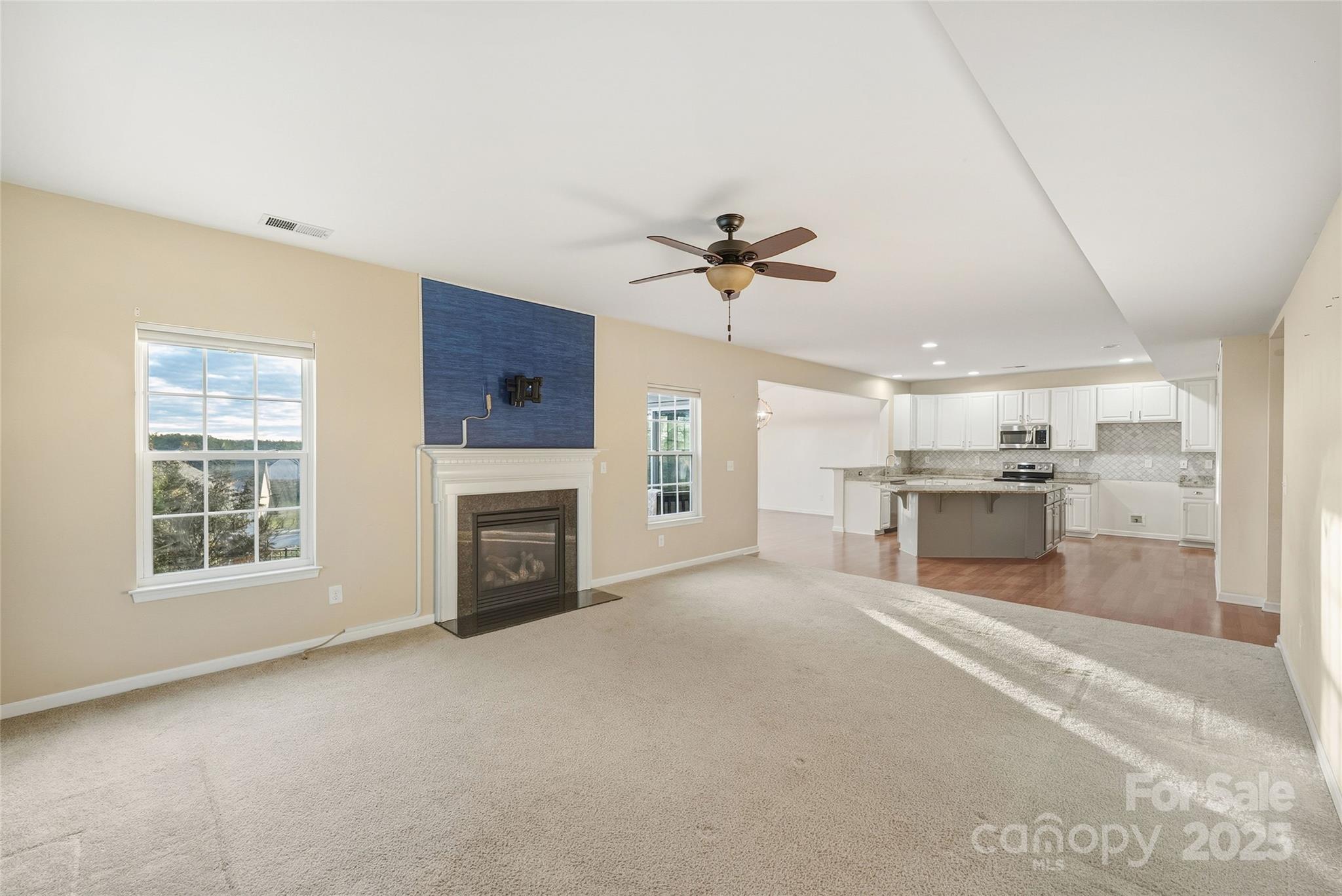 2155 Galloway Lane Southwest Concord, NC 28025 - Photo 5 of 40 a view of a kitchen with a sink a kitchen island wooden floor and a fireplace
