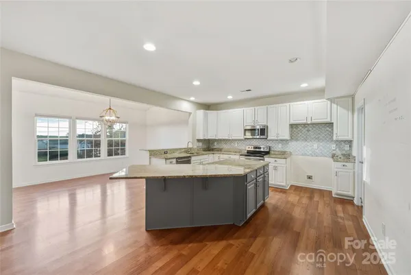 a large kitchen with kitchen island a sink a center island and wooden floor