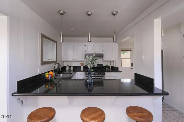 a kitchen with kitchen island a sink dishwasher a stove and a dining table with wooden floor