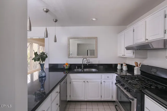 a kitchen with granite countertop a sink a stove and cabinets