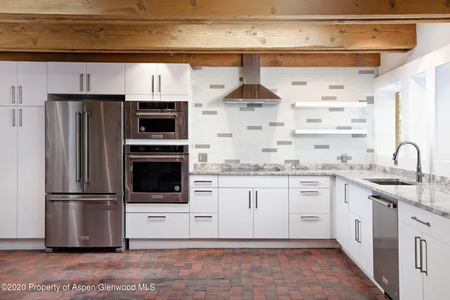 a kitchen with stainless steel appliances kitchen island granite countertop a refrigerator and a sink