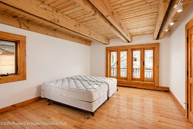 a spacious bedroom with a bed and wooden floor
