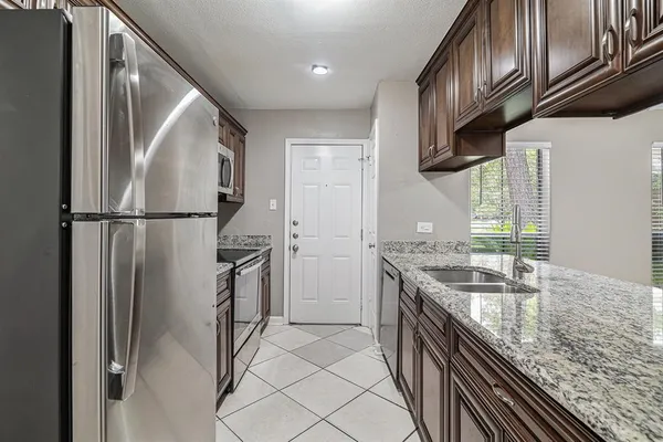 a kitchen with stainless steel appliances granite countertop a refrigerator a stove and a sink