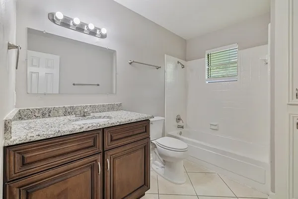 a bathroom with a granite countertop sink a toilet and shower