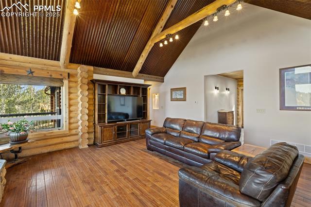 111 Blue Spruce Road Divide, CO 80814 - Photo 13 of 46 Living area featuring beamed ceiling, hardwood / wood-style floors, high vaulted ceiling, and rustic walls