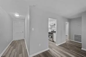 a view of a hallway with wooden floor and a cabinet