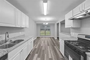 a kitchen with granite countertop a stove a sink dishwasher and cabinets with wooden floor