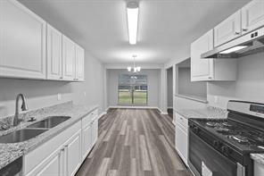 1227 Fair Drive Angleton, TX 77515 - Photo 4 of 18 a kitchen with granite countertop a stove a sink dishwasher and cabinets with wooden floor